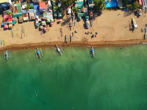 Free Captivating aerial view of a vibrant sandy beach with docked boats in the Philippines. Stock Photo