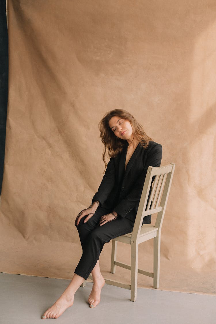 Woman Sitting On Wooden Chair With Eyes Closed