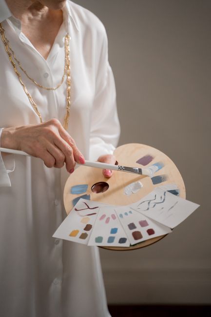 Close-up of a painter blending hues on a wooden palette with swatches.