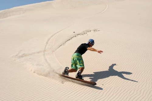 A Man Sandboarding in the Desert