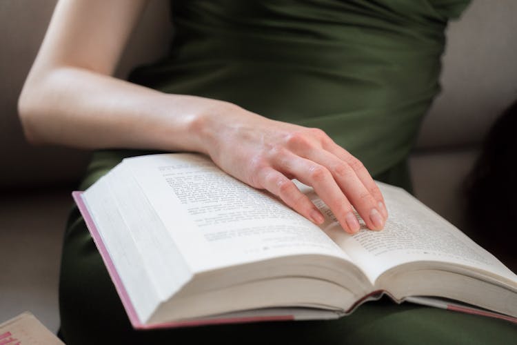 Close Up On Womans Hand On Book On Legs