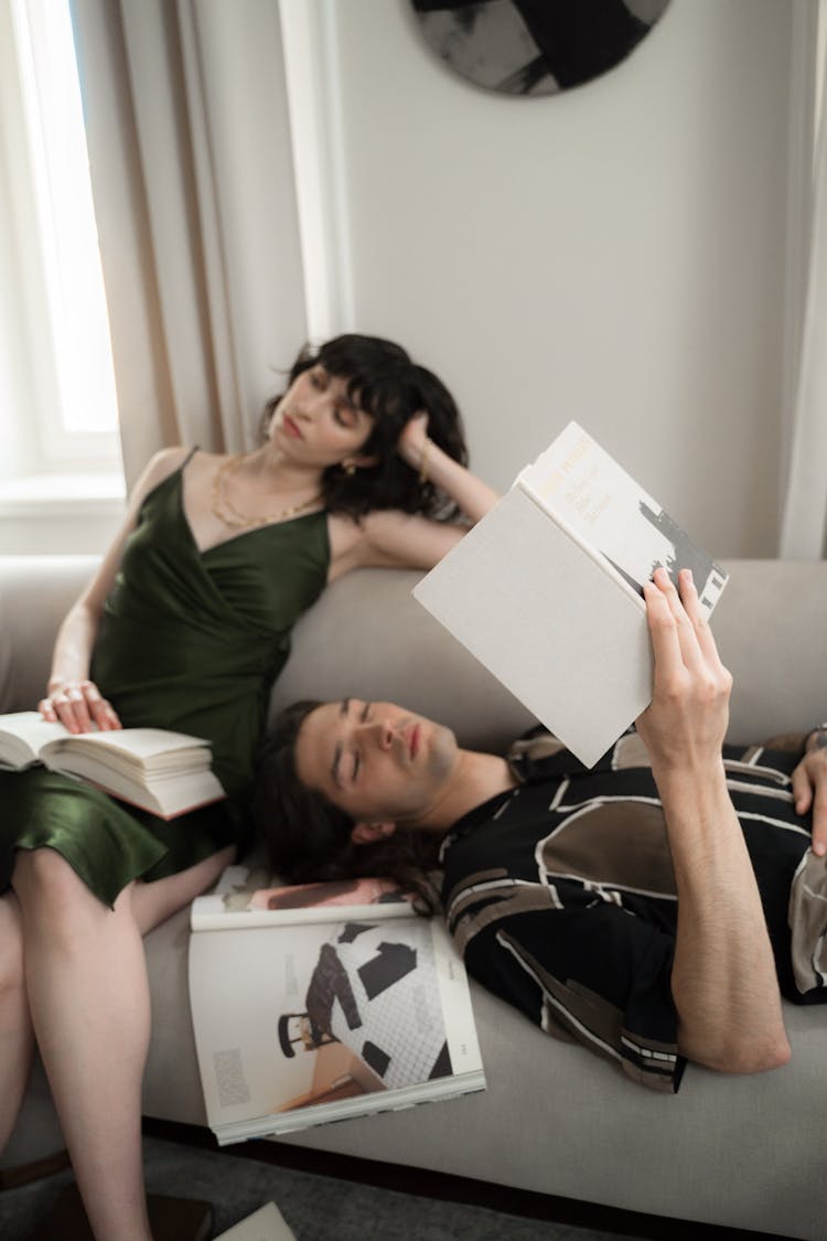 Man And Woman Bored With Books On Bed