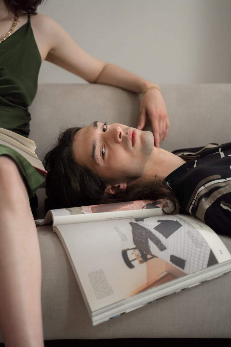 Man Laying On Couch Next To Sitting Woman