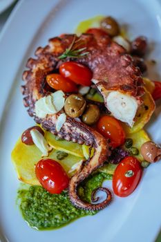Delicious octopus with cherry tomatoes and olives on a stylish plate.