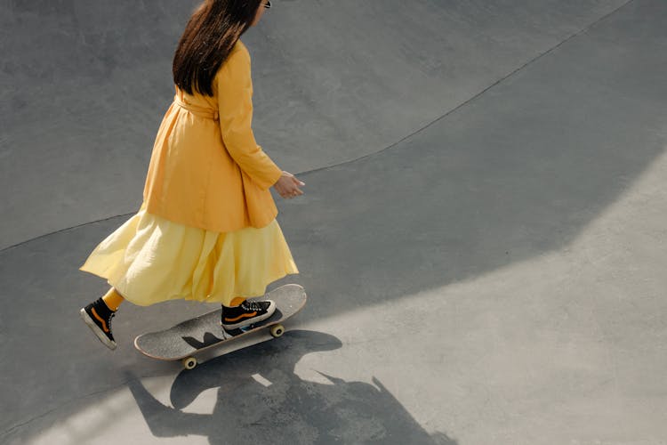 Woman In Yellow Dress Riding A Skateboard