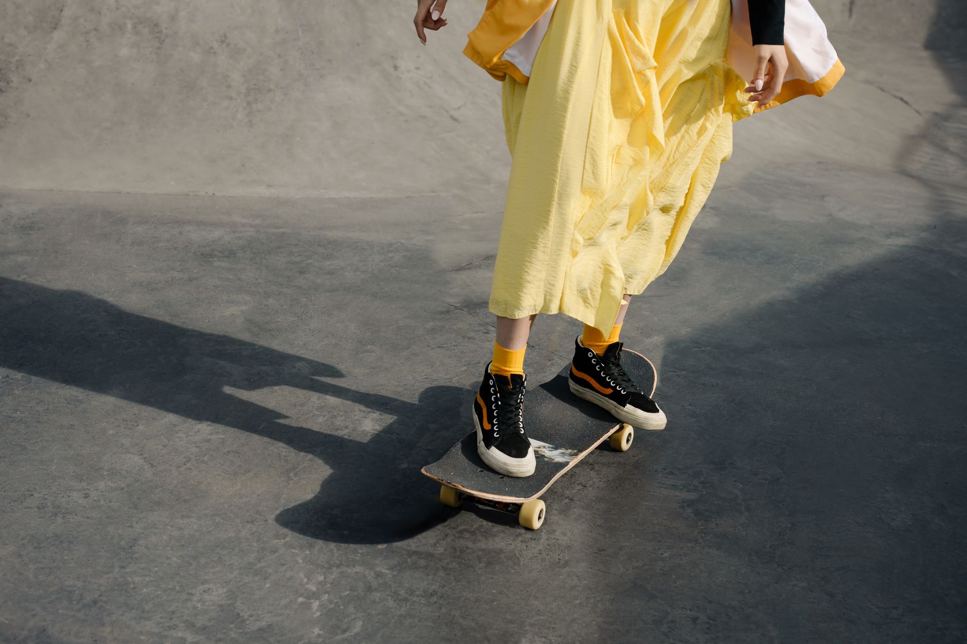 Contemporary skater riding a concrete bowl in Houston, contrasting modern safety gear with vintage skateboard graphics
