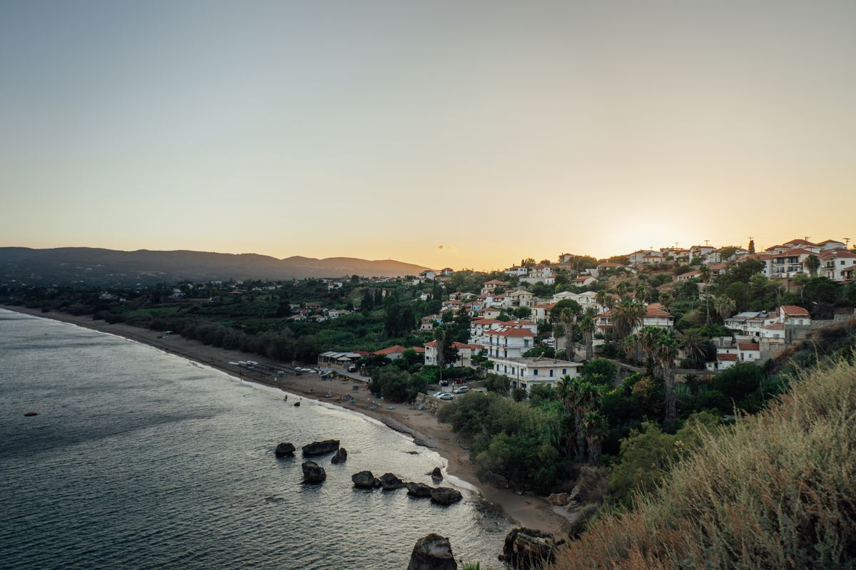Satul de coastă Koroni din Peloponez la apus, cu case tradiționale coborând spre mare