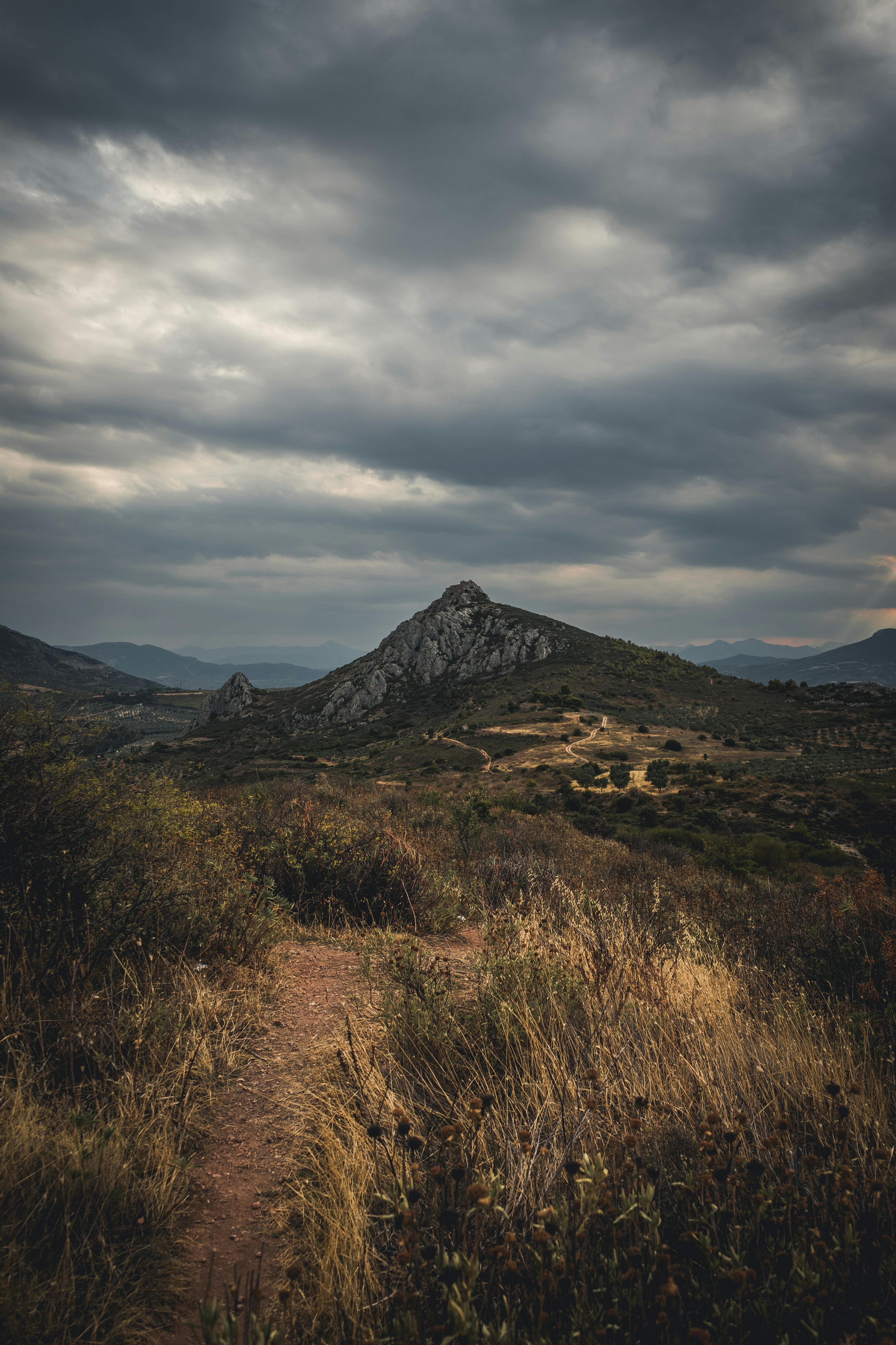 Dramatic aerial view of Corinth's rugged terrain under a cloudy sky, showcasing natural beauty and scenic pathways.