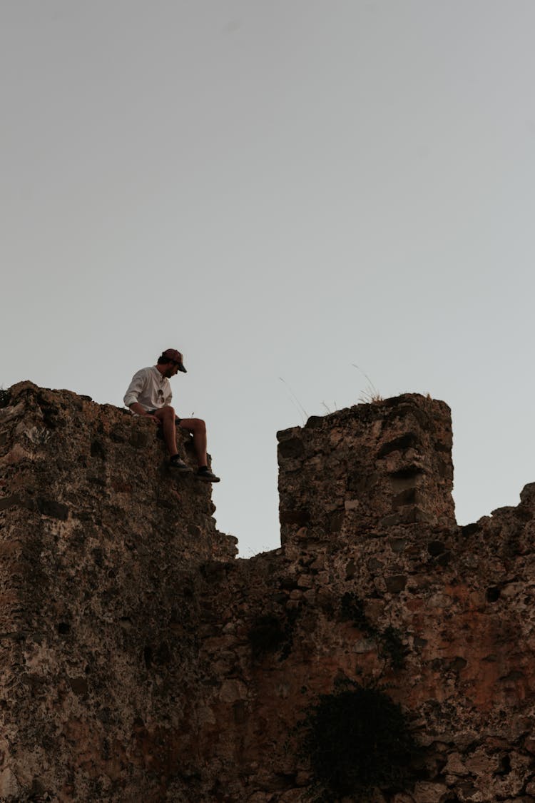 A Person Sitting On A Stone Wall