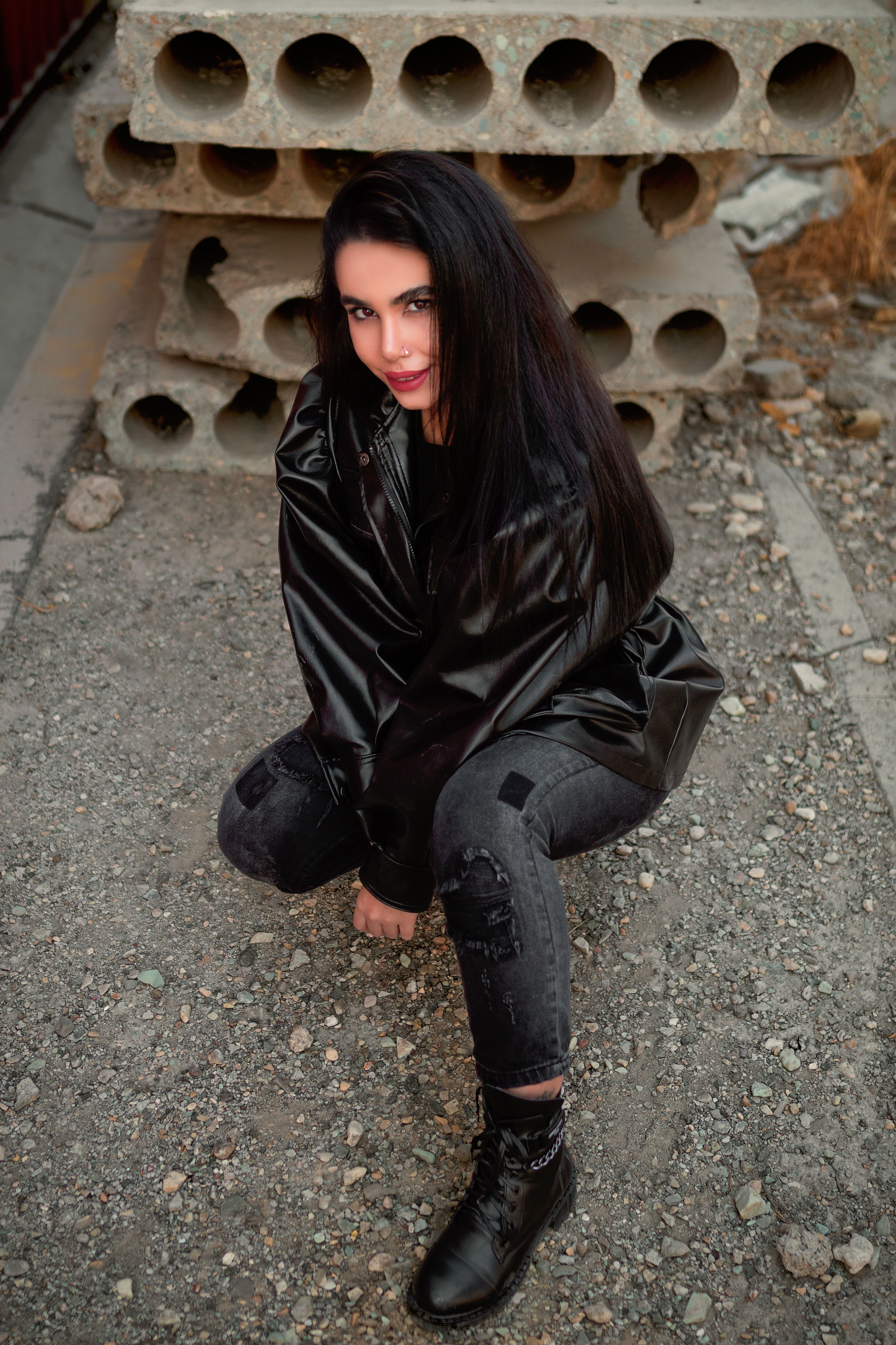 Woman in Black Leather Jacket and Black Pants Sitting on a Ground ...