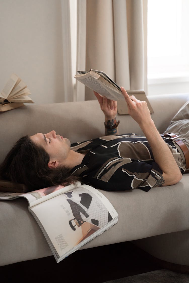 Man Laying On Bed And Reading Book