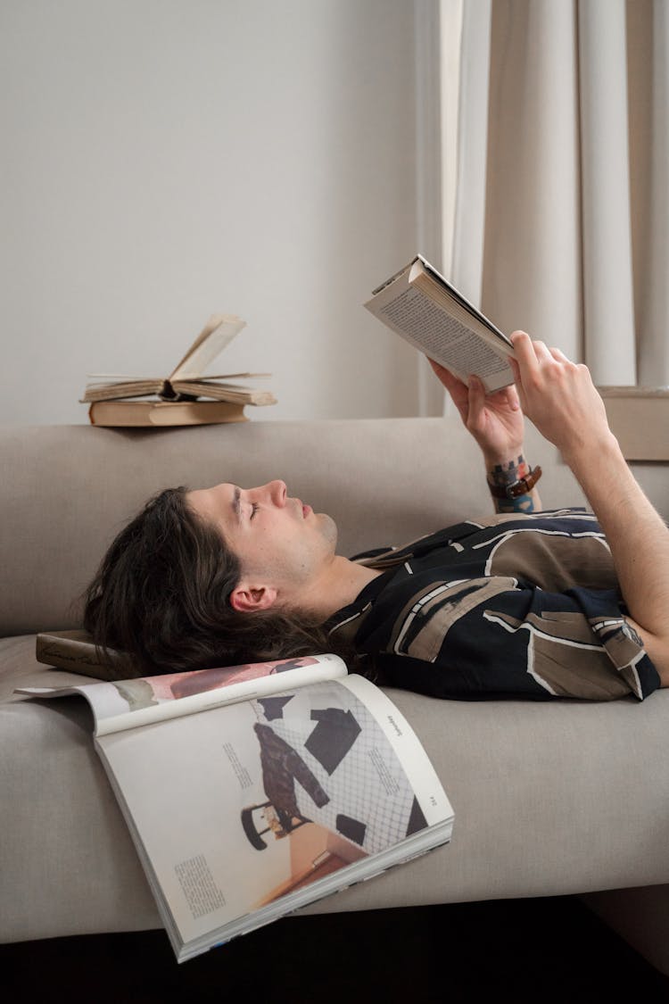 Man Laying On Bed And Reading Book