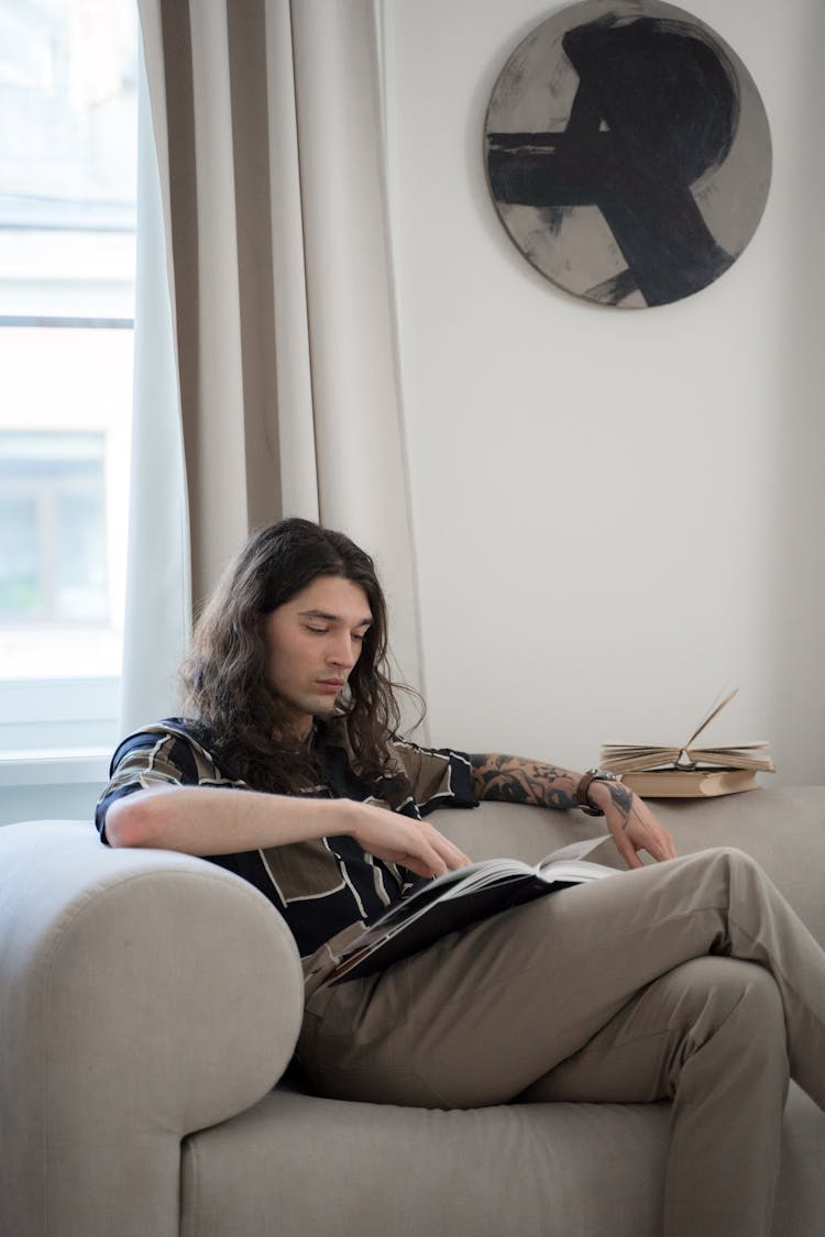 Tattooed Man With Book On Bed