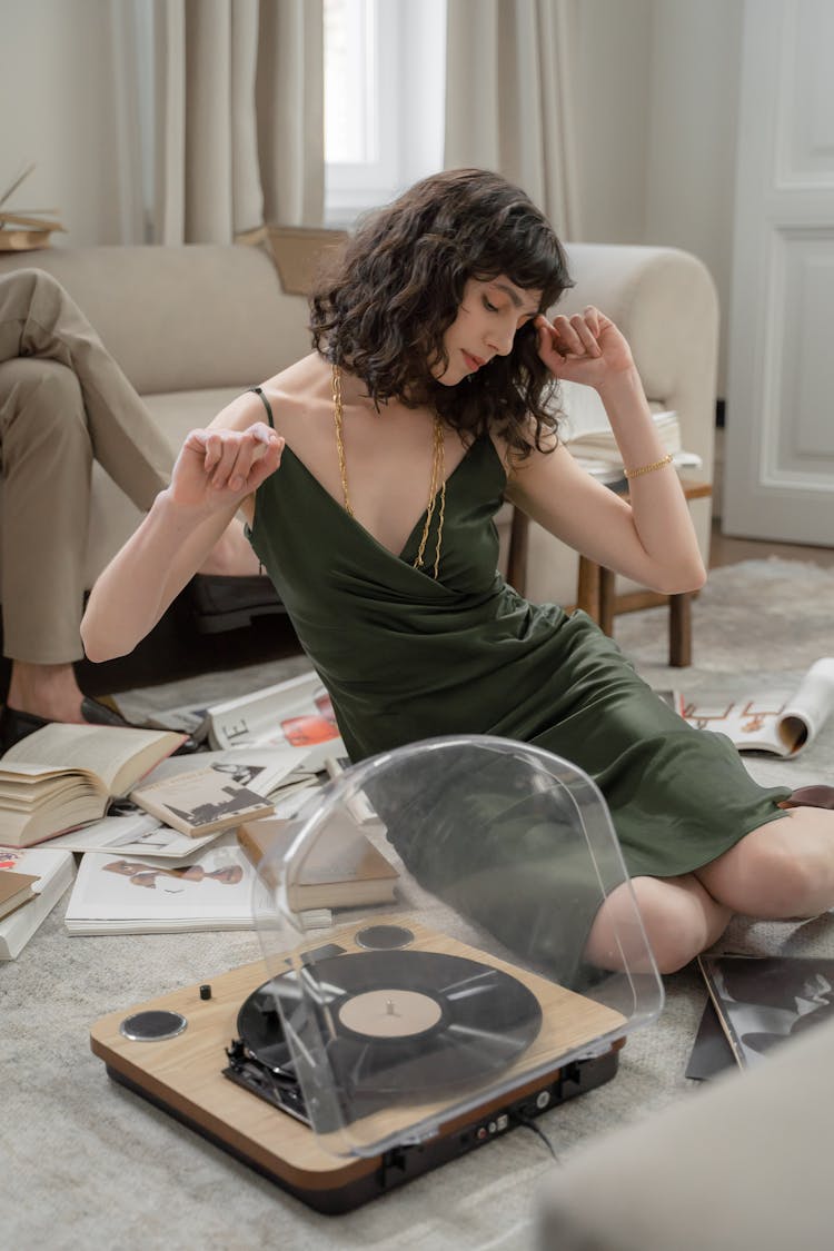 Woman Listening To Music From Vinyl Recorder On Floor