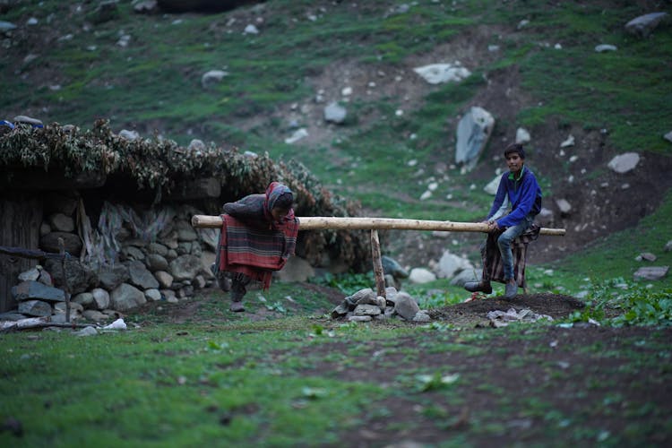 Kids Riding A Wooden Seesaw In The Mountains