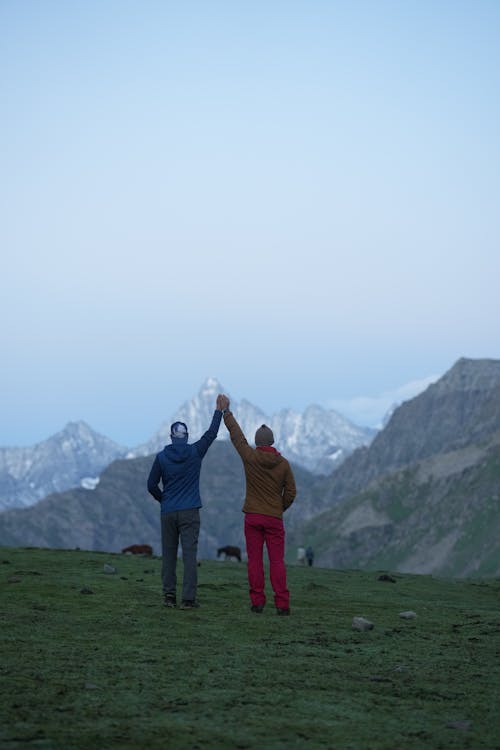 Free Two People Holding Hands and Raising it While in the Mountains Stock Photo