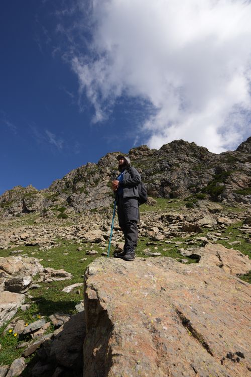 Free A lone hiker stands on a rocky mountain, gazing at the expansive landscape under a clear blue sky. Stock Photo