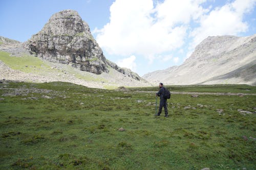 Free A Man Standing in the Grassy Mountain Valley Stock Photo