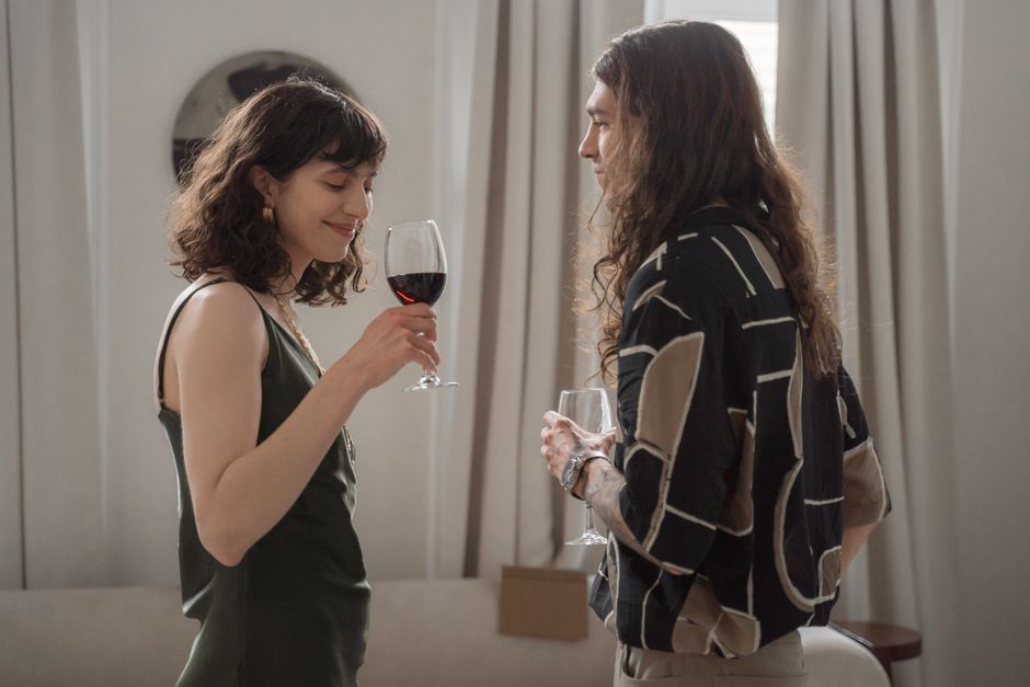 A couple enjoys wine together in a cozy indoor setting, sharing a pleasant moment.