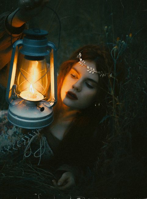 A woman holding a vintage lantern in a dark, moody setting, creating an enigmatic atmosphere.