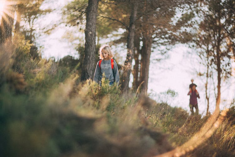 Portrait Of Kid With Backpack Walking On Grass