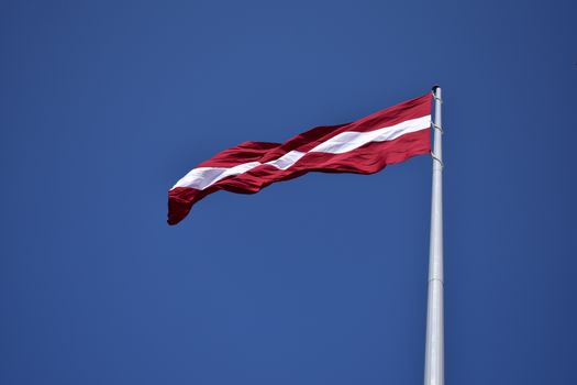 Red and White State Flag Waving Under Blue Sky at Daytime