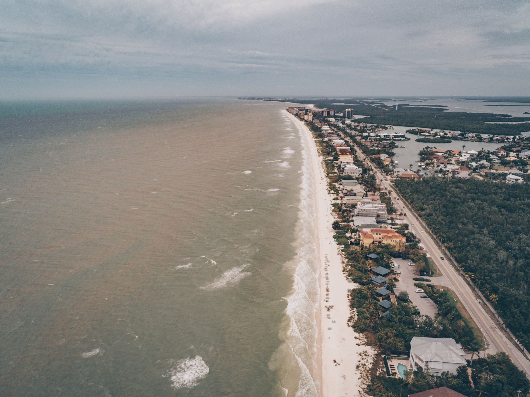 A stunning aerial view of a coastal seaside town showcasing beaches, buildings, and the ocean.