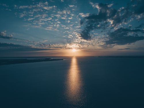 Free A tranquil ocean scene at sunset with dramatic clouds and shimmering reflections on the water. Stock Photo