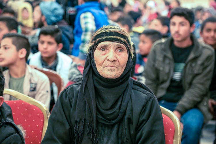 An Elderly Sitting Among A Crowd Of People