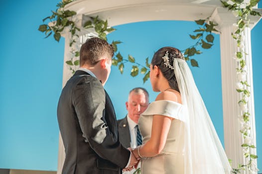 Bride and groom holding hands in an outdoor ceremony under a floral arch.