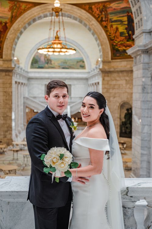Free Romantic newlywed couple posing in an elegant architectural setting with arches. Stock Photo