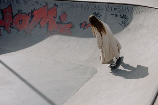 A skateboarder in a trench coat rides through a graffiti-decorated skatepark.