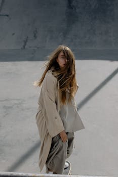 Young woman skateboarding in a stylish outfit at an urban skate park on a sunny day.