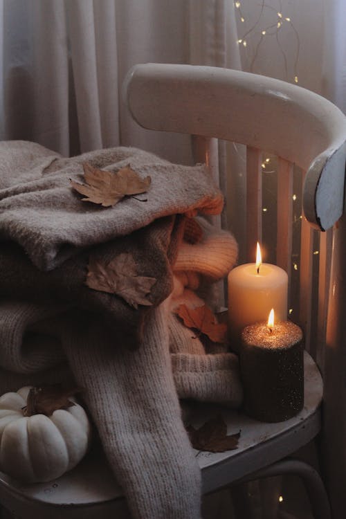 Free Lighted Candles Beside Knitted Sweaters Stock Photo