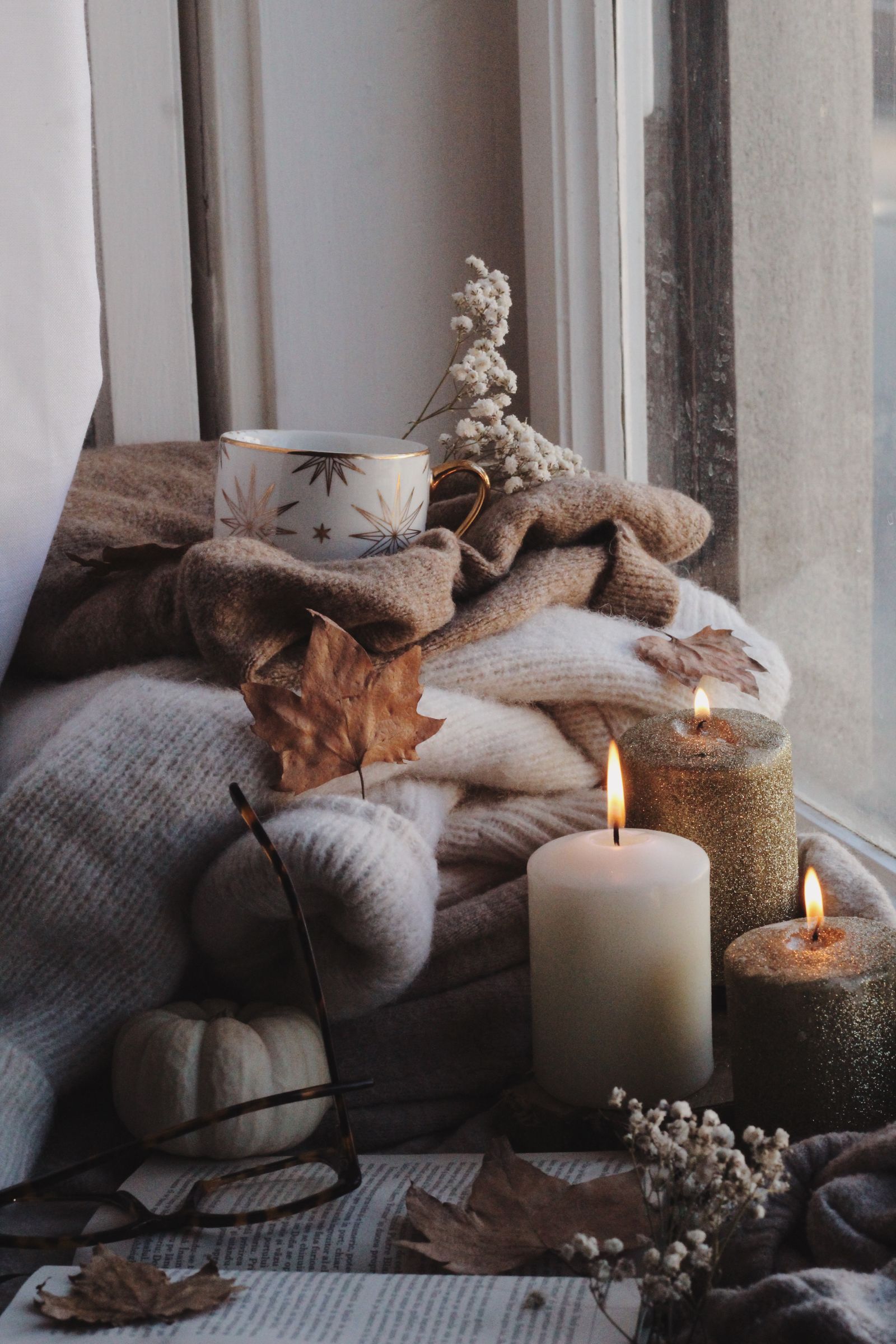 Candles, tea and a knit blanket on a windowsill
