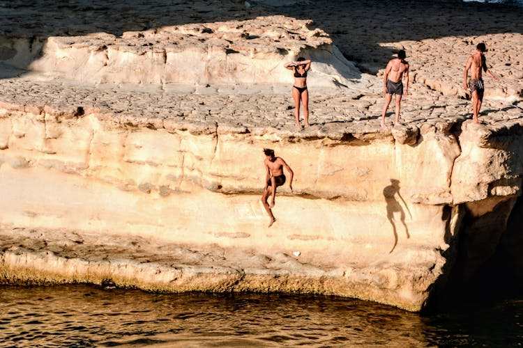 A Shirtless Man Jumping On The Cliff