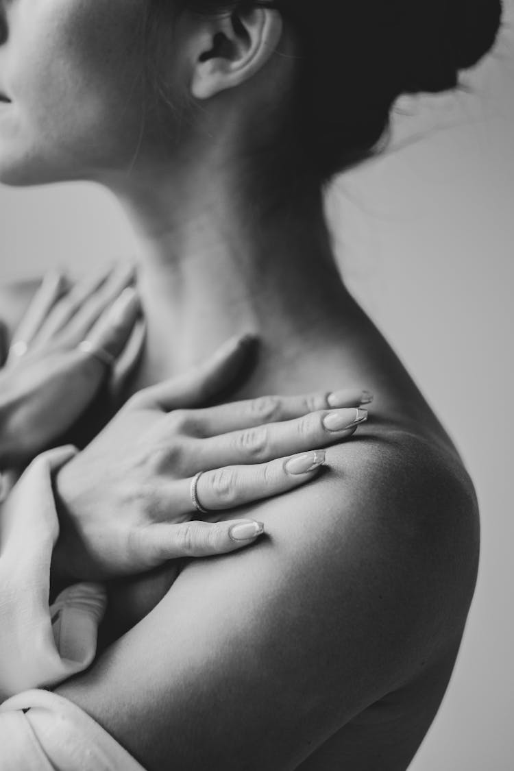 A Grayscale Photo Of Woman Touching Her Shoulders