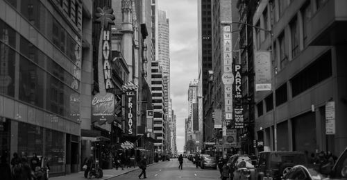 Free Black and white cityscape of a busy urban street in New York City with skyscrapers and signs. Stock Photo