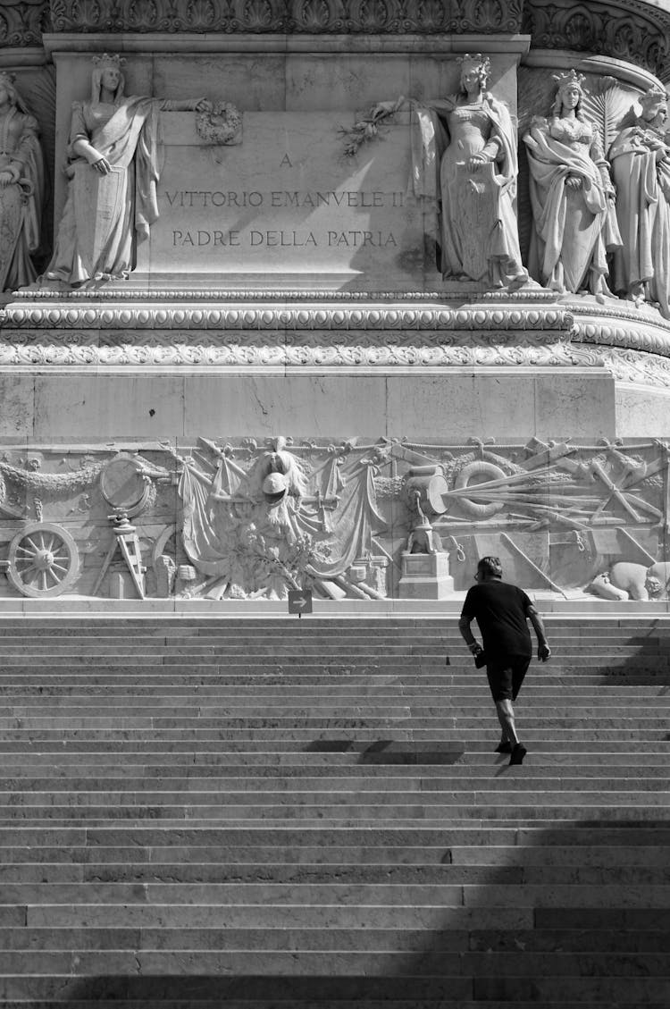 Man Walking Up The Steps To The Statues In Black And White