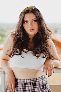 Portrait of a confident young woman in casual summer fashion standing outdoors with long wavy hair.