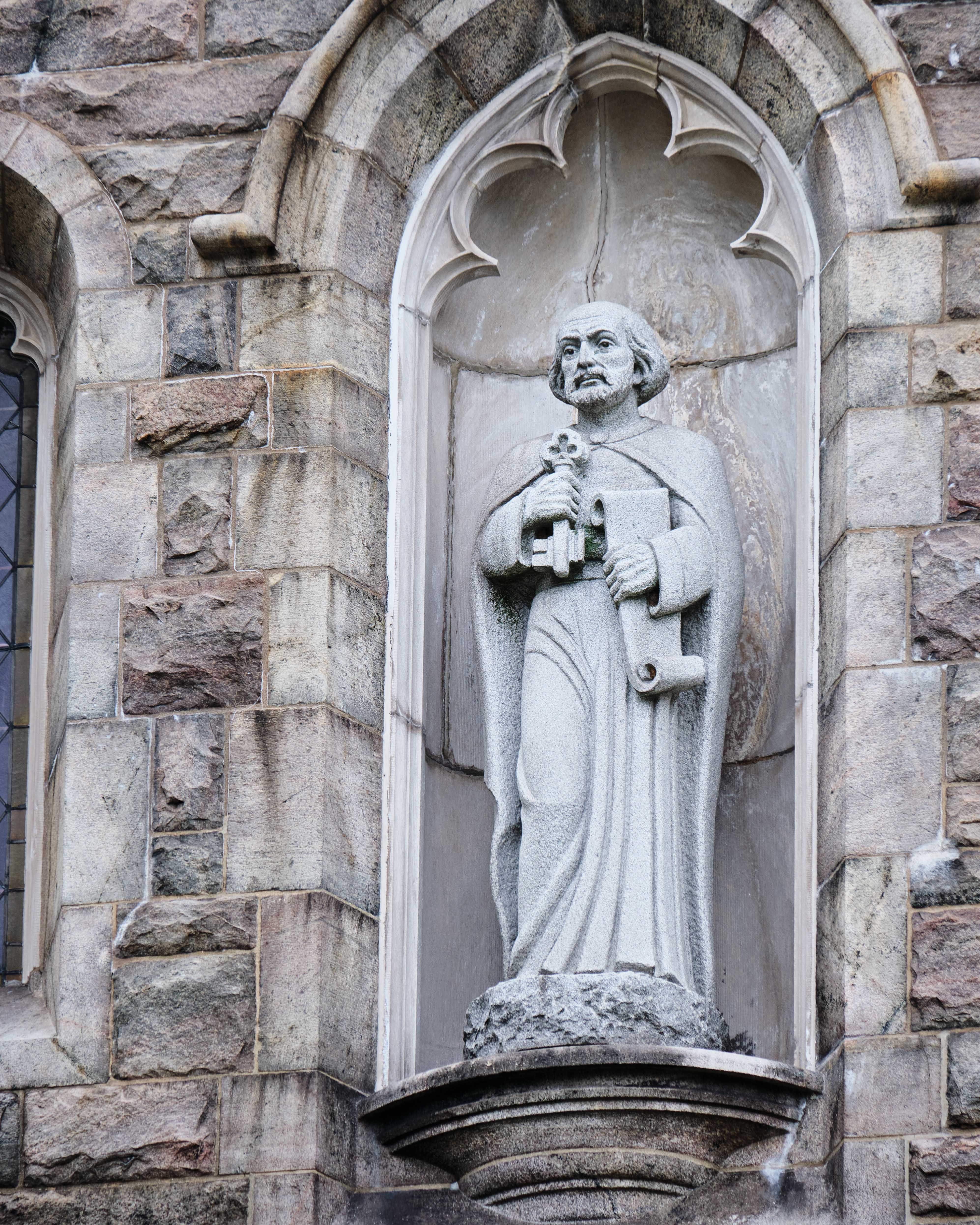 Detailed image of a Gothic-style stone statue inset in the facade of a church.