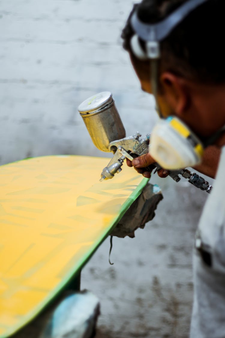 Man Spray Painting Piece Of Wood