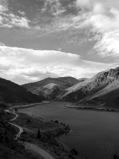 Grayscale Photo of Mountains near the River