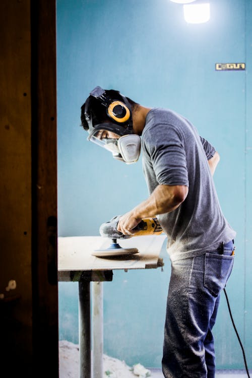 Man in Blue Shirt Polishing a Surface Wearing Mask