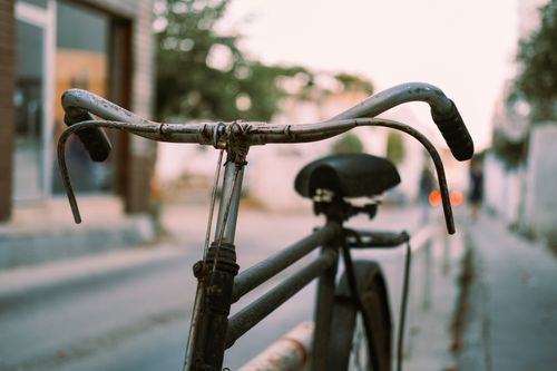 Free Rustic vintage bicycle with blurred street background and warm lighting. Stock Photo