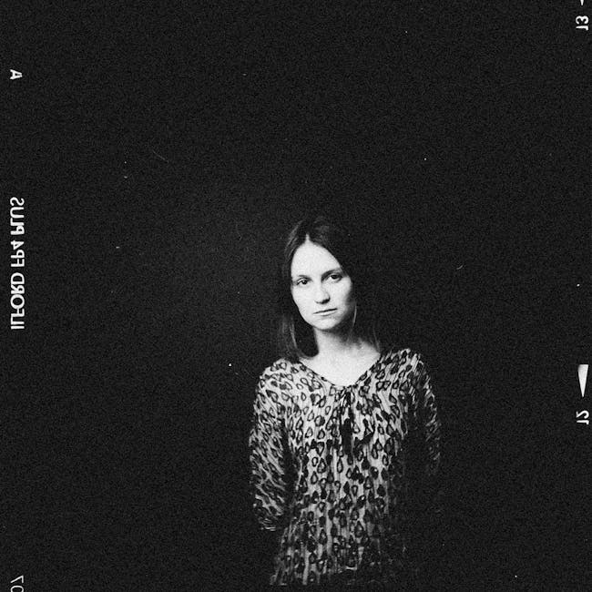 Black and white portrait of a young woman with a leopard print top, exuding a nostalgic mood.