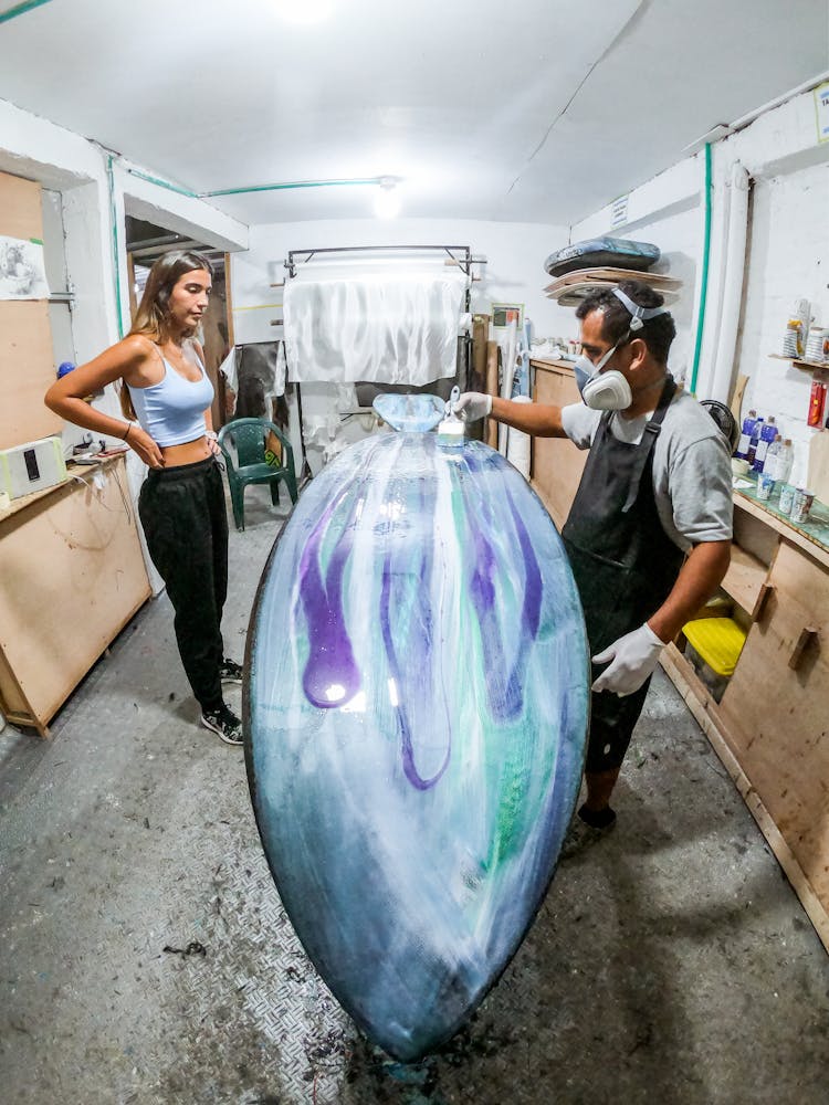 Man And Woman Painting Surfboard 