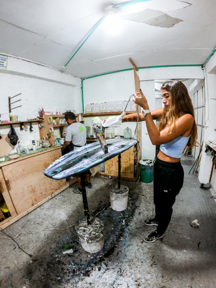 Woman Waxing A Surfboard 