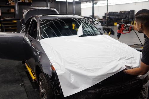 Free Car being wrapped with white vinyl in an auto workshop by a skilled mechanic. Stock Photo