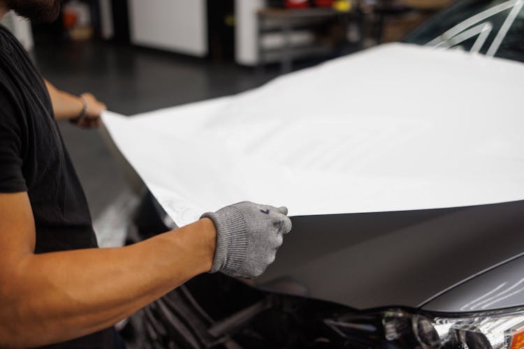 Person Wrapping Car Hood With Paper
